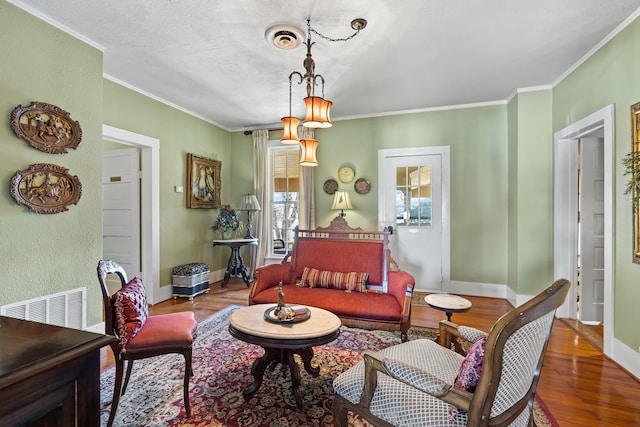 living room with wood-type flooring, ornamental molding, and a textured ceiling