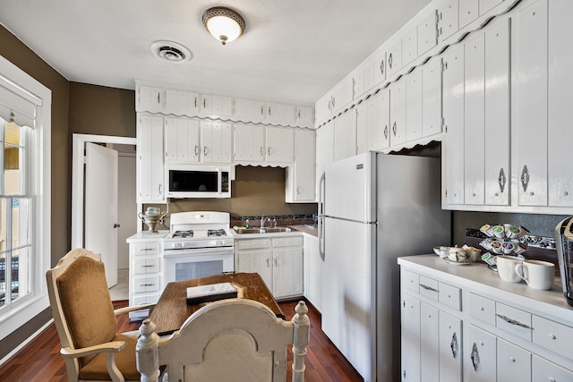 kitchen featuring dark hardwood / wood-style flooring, sink, white appliances, and white cabinets