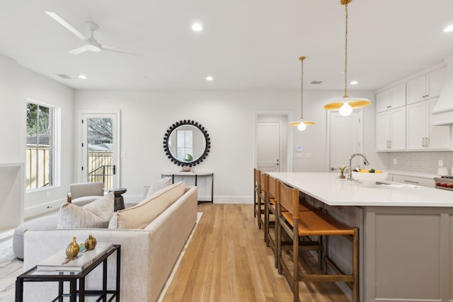 living room featuring ceiling fan, sink, and light wood-type flooring