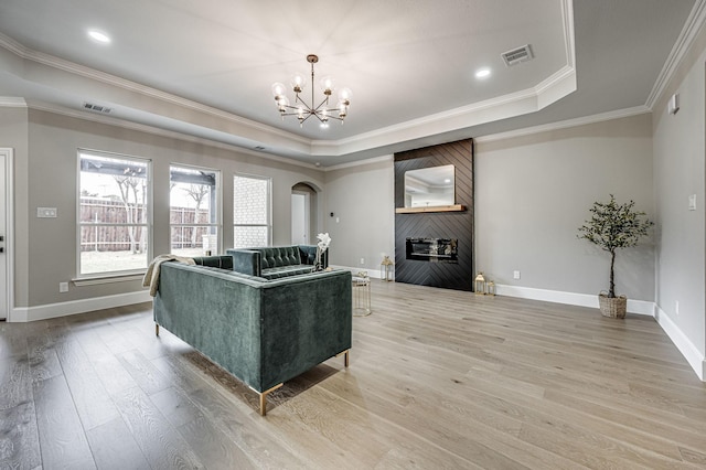 living room with arched walkways, wood finished floors, a raised ceiling, and visible vents