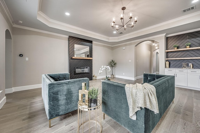 living area featuring arched walkways, visible vents, a fireplace, and a tray ceiling