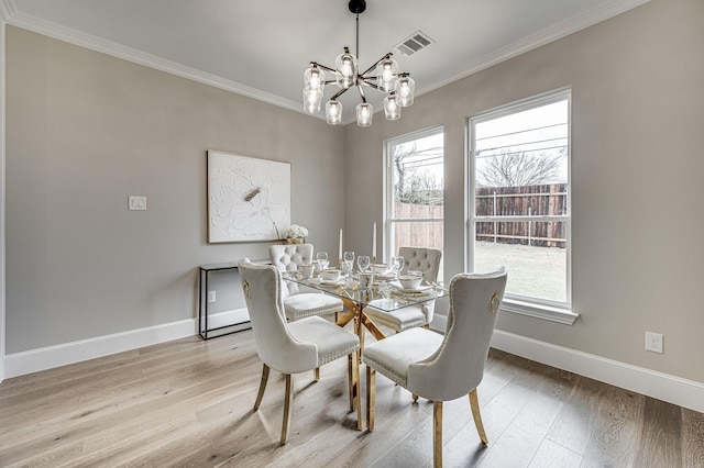 dining space featuring ornamental molding, light wood-style flooring, visible vents, and an inviting chandelier