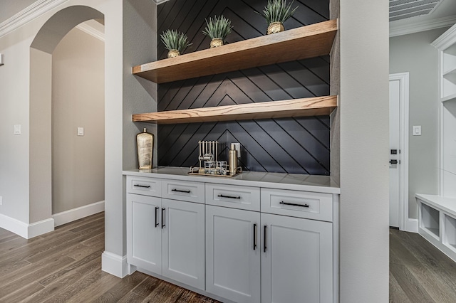 bar with dark wood-style floors, arched walkways, crown molding, and baseboards