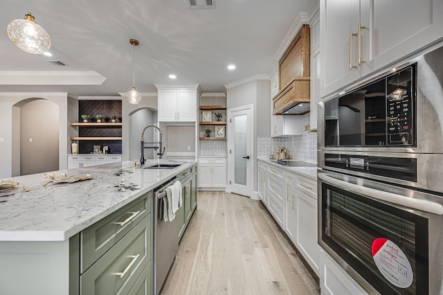 kitchen with arched walkways, pendant lighting, white cabinets, and a sink