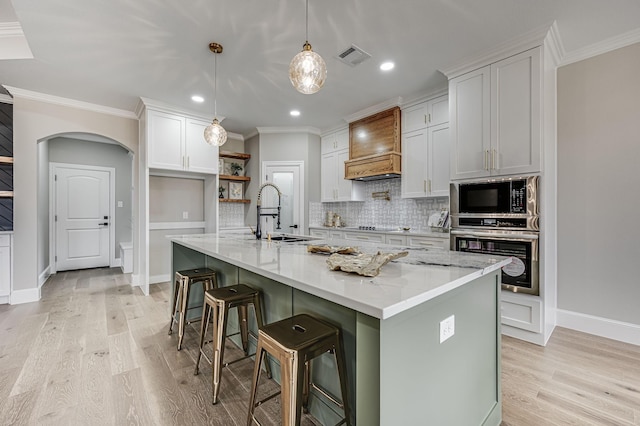 kitchen featuring a sink, white cabinetry, black appliances, an island with sink, and custom range hood