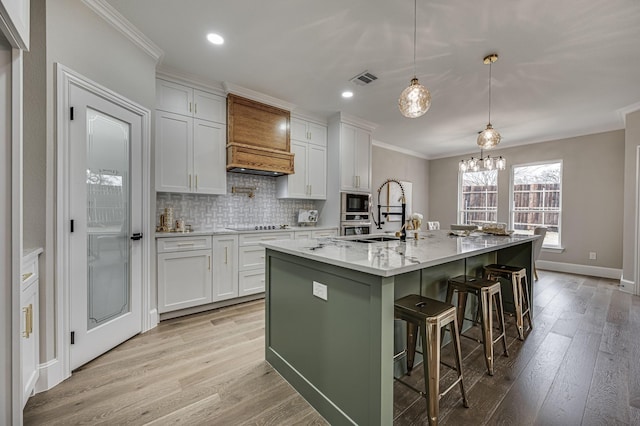 kitchen with white cabinets, a center island with sink, and decorative light fixtures