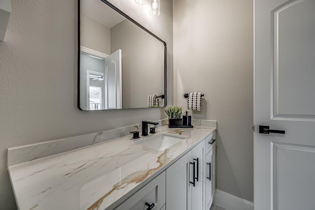 bathroom with a textured wall, vanity, and baseboards