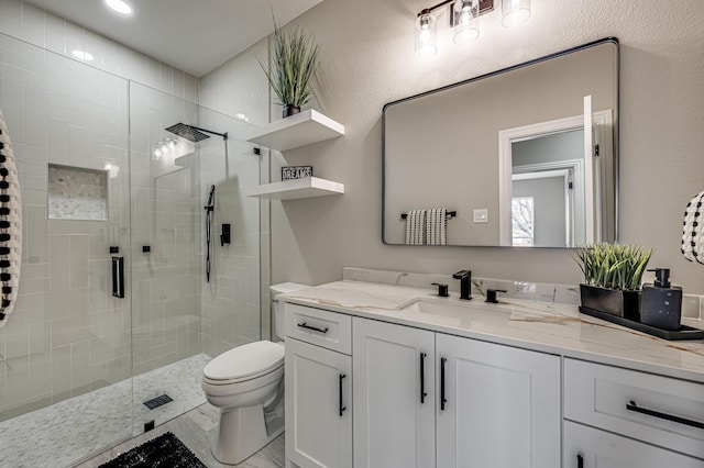 bathroom featuring a textured wall, toilet, vanity, and a shower stall