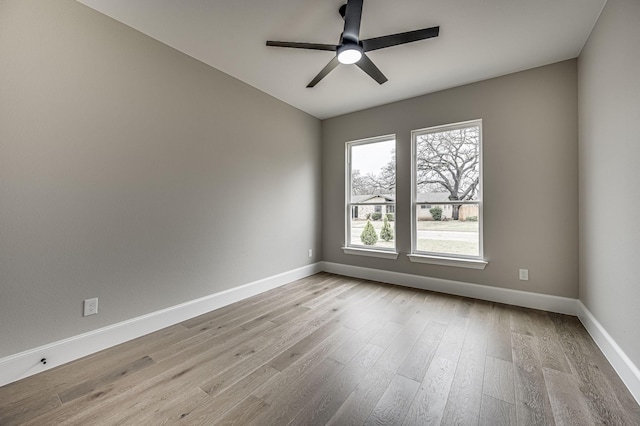 spare room featuring light wood-style floors, baseboards, and a ceiling fan