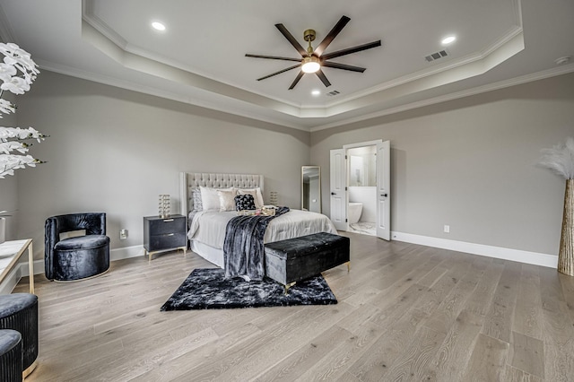 bedroom featuring light wood-type flooring, a raised ceiling, and visible vents