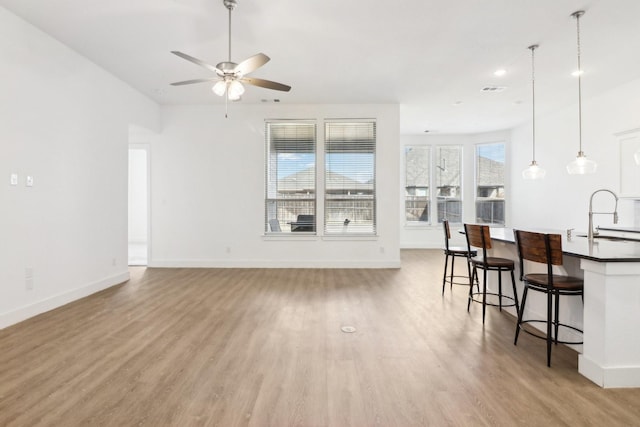 living room featuring sink, light hardwood / wood-style flooring, and ceiling fan