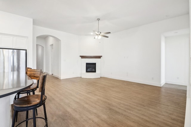 living room with ceiling fan, a fireplace, and light hardwood / wood-style floors