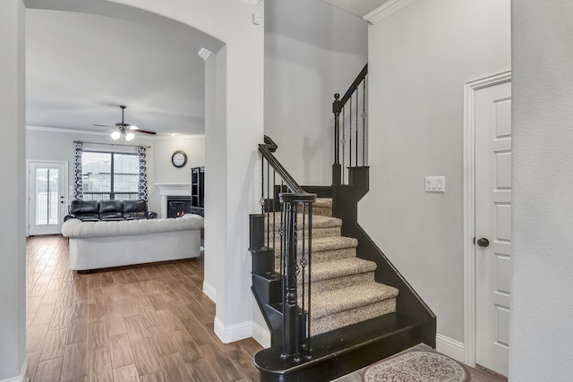 stairway featuring hardwood / wood-style floors, ornamental molding, and ceiling fan