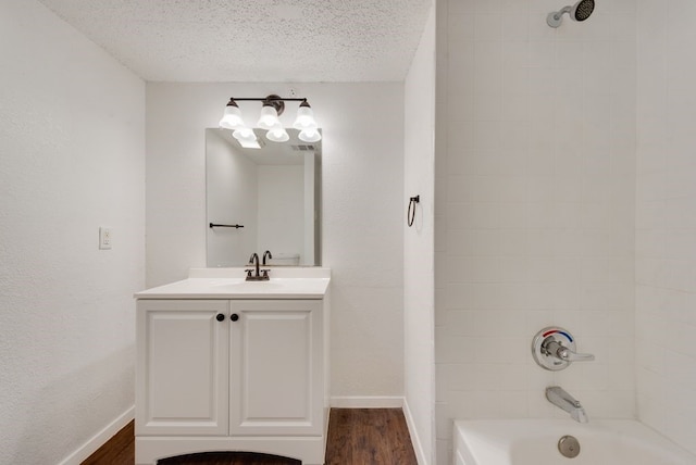 bathroom featuring hardwood / wood-style flooring, tiled shower / bath, vanity, and a textured ceiling