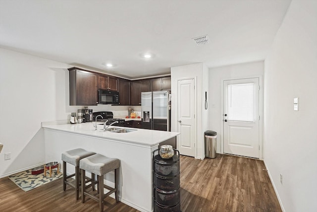 kitchen featuring dark wood-type flooring, dark brown cabinetry, sink, kitchen peninsula, and black appliances