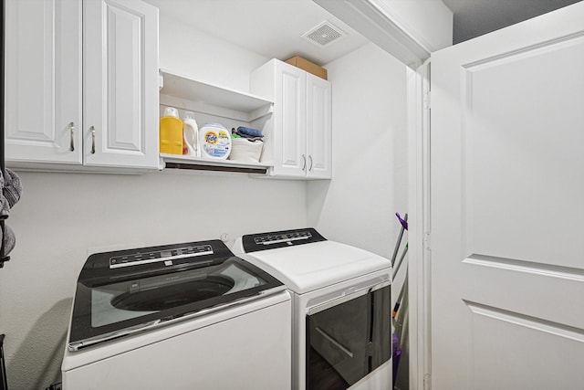 clothes washing area featuring cabinets and washing machine and dryer