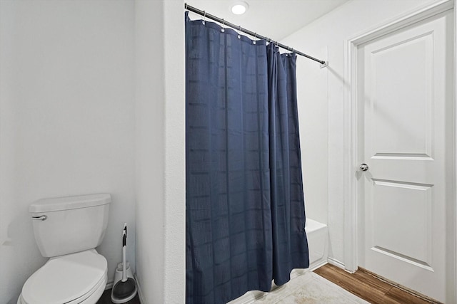 bathroom with hardwood / wood-style floors, shower / tub combo with curtain, and toilet