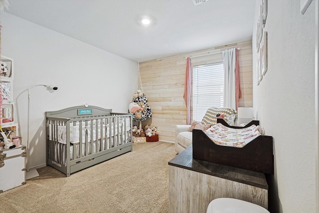 bedroom featuring a crib, carpet floors, and wooden walls