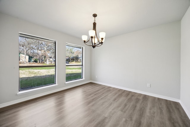 empty room with dark wood-type flooring and a notable chandelier