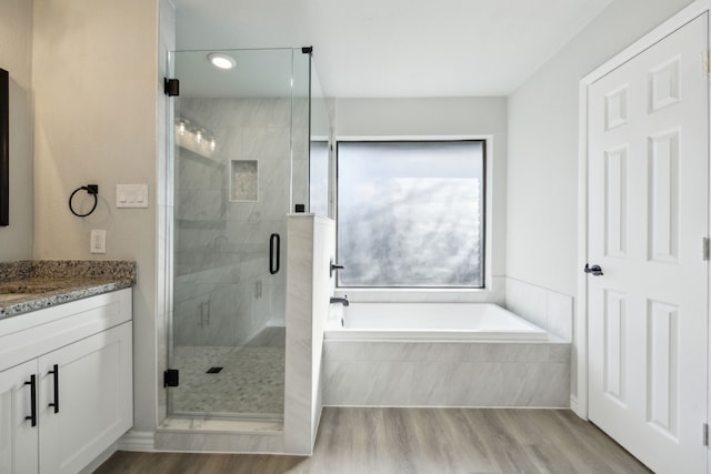 bathroom with vanity, hardwood / wood-style floors, and plus walk in shower