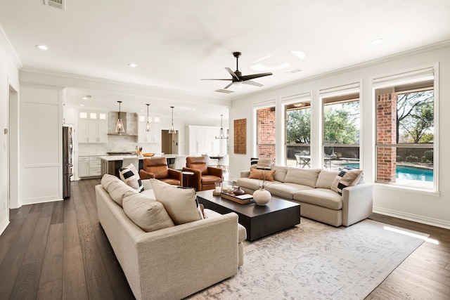 living room with crown molding, wood-type flooring, and ceiling fan with notable chandelier