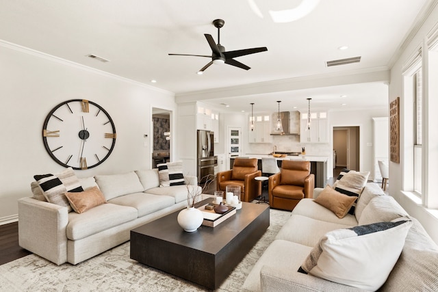 living room with ornamental molding, a healthy amount of sunlight, ceiling fan, and light hardwood / wood-style floors