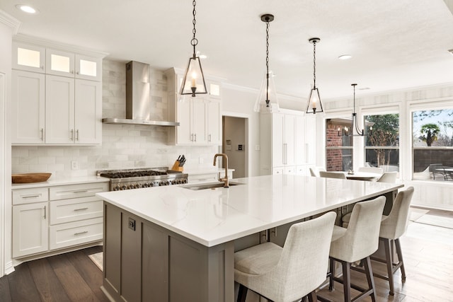 kitchen featuring white cabinets, decorative light fixtures, sink, and wall chimney exhaust hood