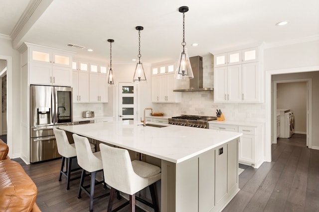 kitchen featuring white cabinets, a kitchen island with sink, stainless steel fridge, and wall chimney exhaust hood