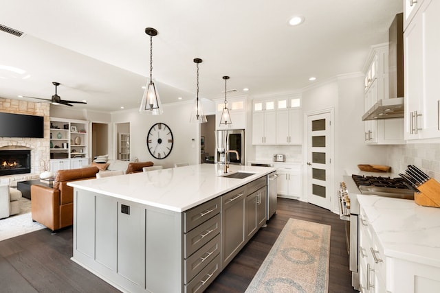 kitchen featuring wall chimney exhaust hood, sink, stainless steel appliances, a large island, and white cabinets