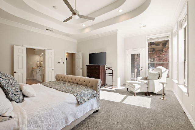 carpeted bedroom featuring ceiling fan, ensuite bath, ornamental molding, and a tray ceiling