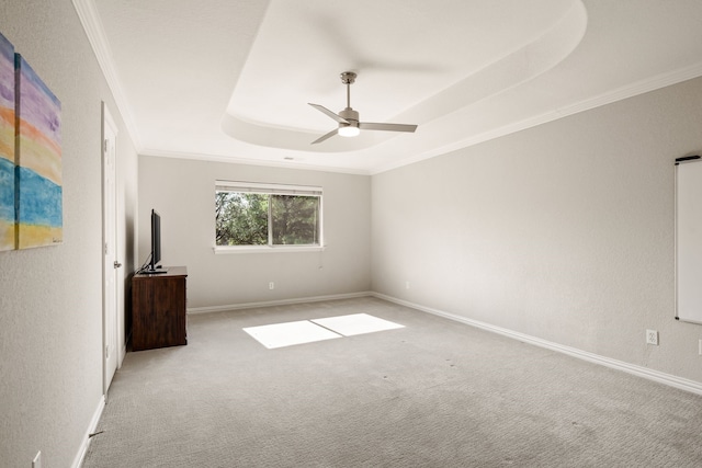 spare room featuring a tray ceiling, ornamental molding, light colored carpet, and ceiling fan