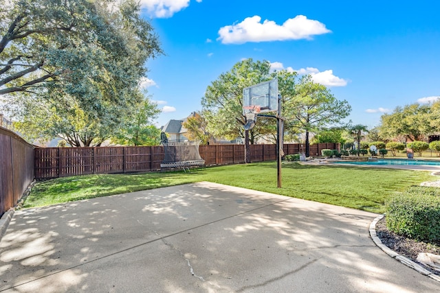 view of basketball court with a yard, a fenced in pool, and a trampoline