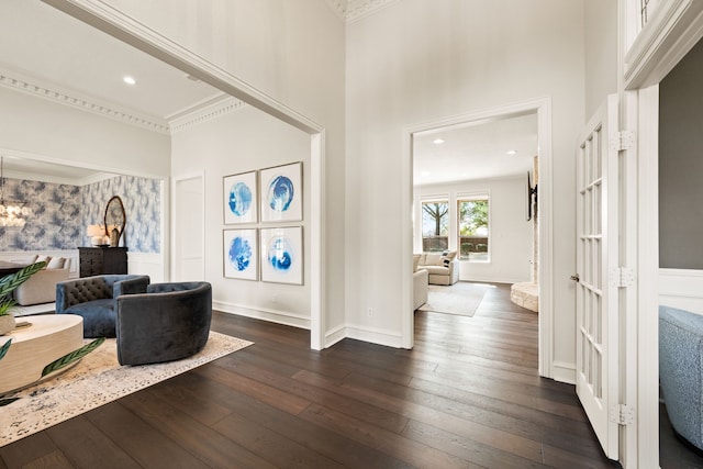 entryway with dark wood-type flooring, a towering ceiling, and ornamental molding