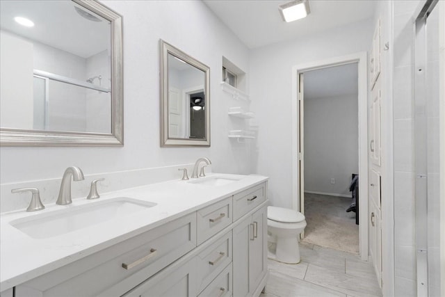 bathroom with vanity, toilet, and a shower with door