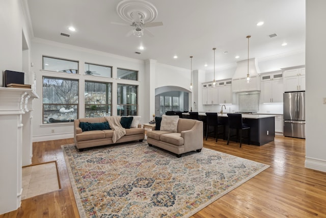 living room with hardwood / wood-style flooring, crown molding, and ceiling fan