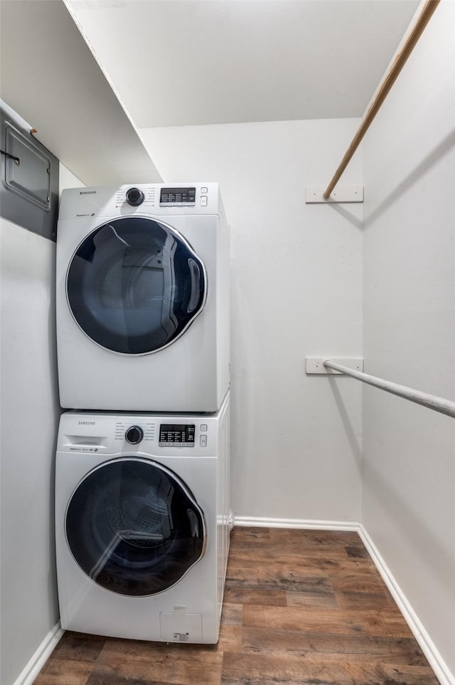 laundry room with dark hardwood / wood-style floors and stacked washer / dryer