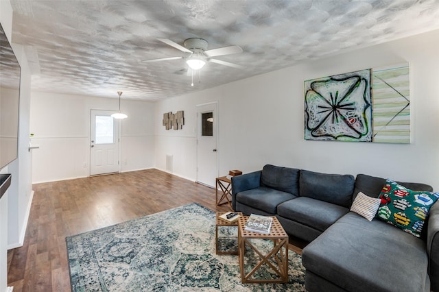 living room featuring ceiling fan, dark hardwood / wood-style floors, and a textured ceiling