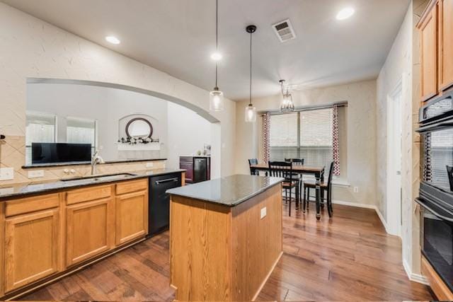 kitchen featuring sink, dark wood-type flooring, hanging light fixtures, a center island, and black appliances