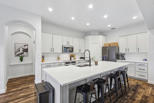 kitchen with sink, stainless steel appliances, white cabinetry, and a kitchen island with sink