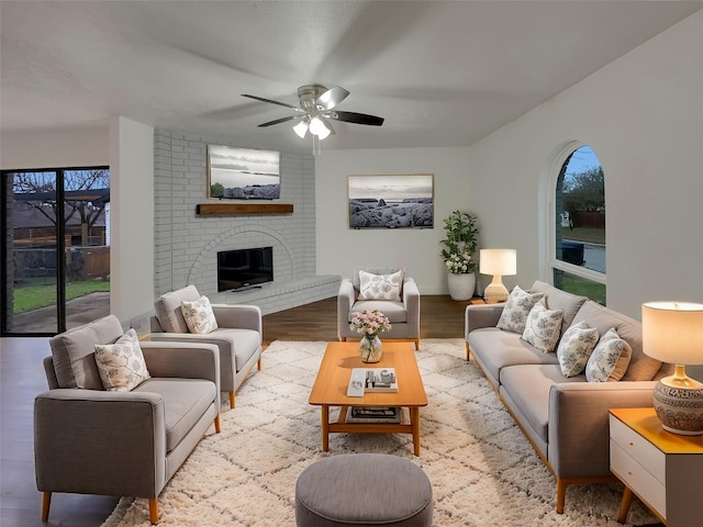 living room with ceiling fan, light hardwood / wood-style floors, and a brick fireplace