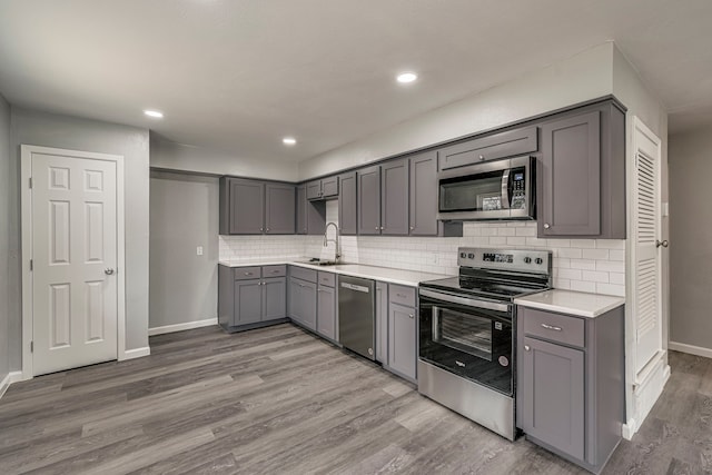 kitchen featuring stainless steel appliances, gray cabinets, sink, and hardwood / wood-style floors