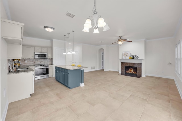 kitchen with sink, blue cabinetry, stainless steel appliances, a center island, and decorative light fixtures