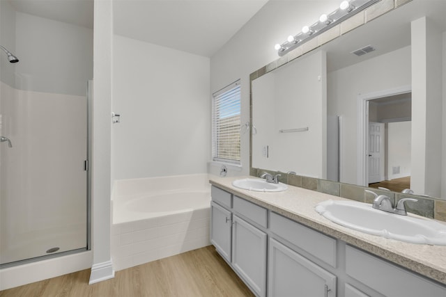 bathroom with vanity, hardwood / wood-style flooring, and plus walk in shower