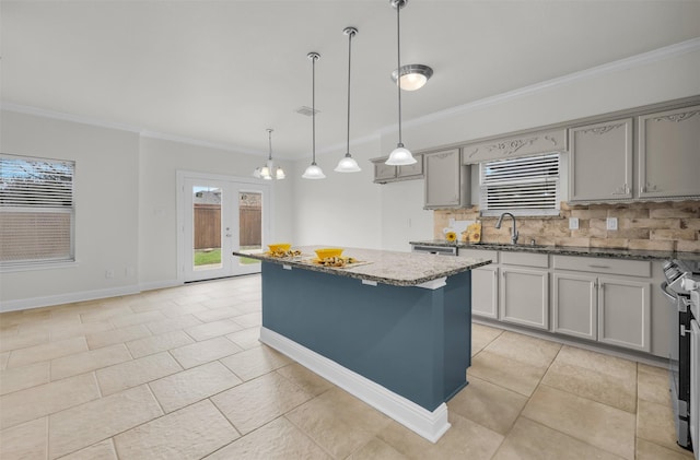 kitchen with sink, hanging light fixtures, gray cabinets, a kitchen island, and dark stone counters