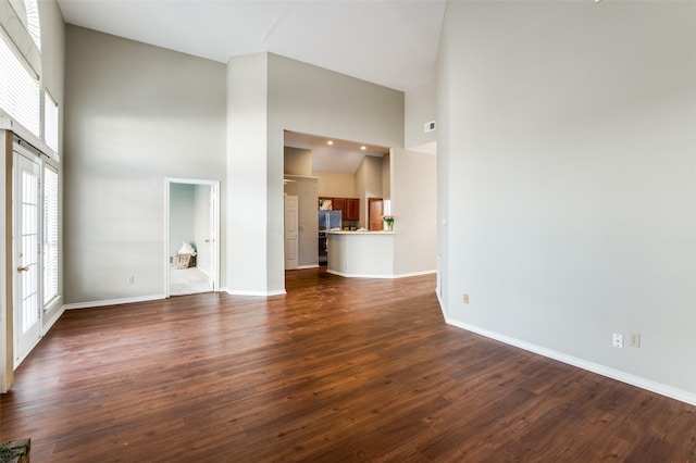 unfurnished living room with hardwood / wood-style floors, french doors, and a high ceiling