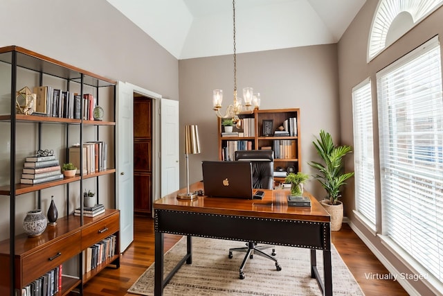 home office with an inviting chandelier, high vaulted ceiling, and dark hardwood / wood-style floors