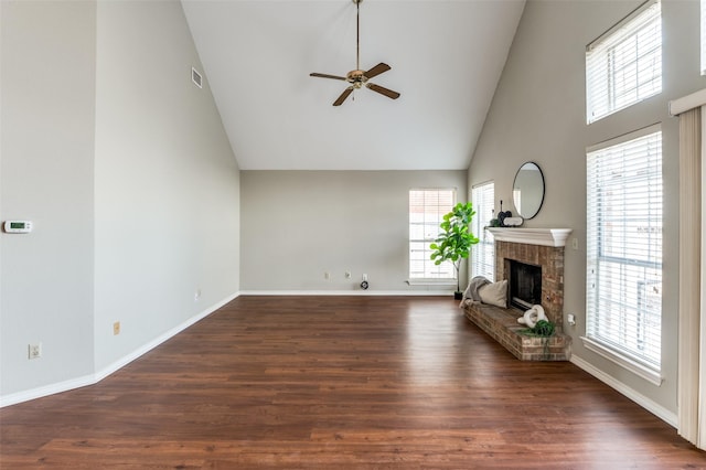 unfurnished living room featuring a brick fireplace, a wealth of natural light, dark wood-type flooring, and high vaulted ceiling