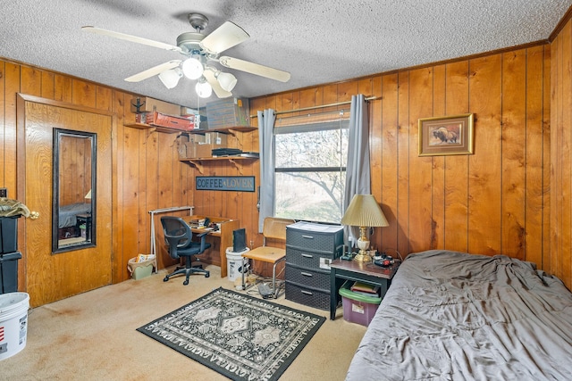 bedroom featuring ceiling fan, carpet flooring, wooden walls, and a textured ceiling