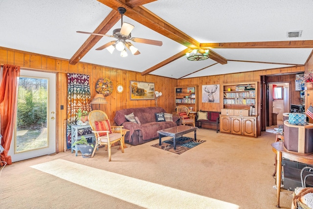 carpeted living room featuring plenty of natural light, lofted ceiling with beams, a textured ceiling, and wood walls