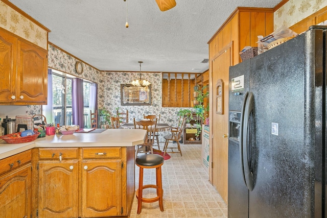 kitchen featuring ornamental molding, a textured ceiling, decorative light fixtures, black refrigerator with ice dispenser, and kitchen peninsula